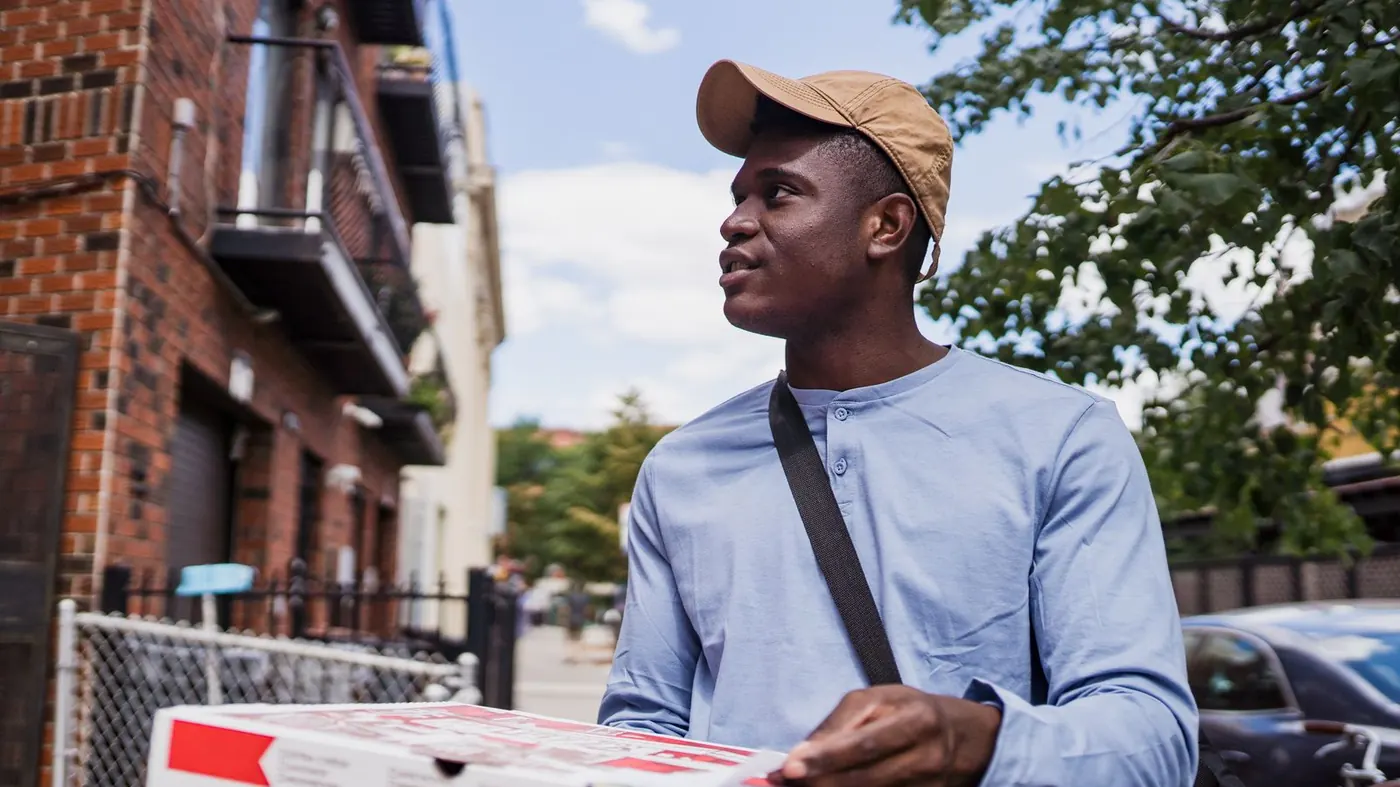 Delivery driver carrying a pizza box